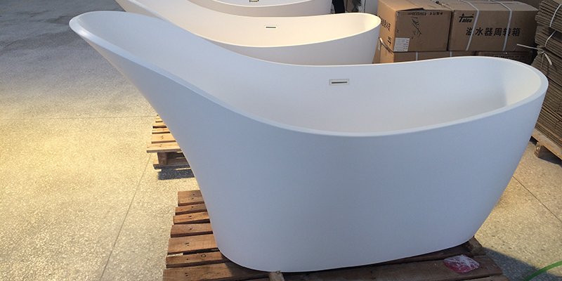 A hand buffing out a minor scratch on a solid surface bathtub