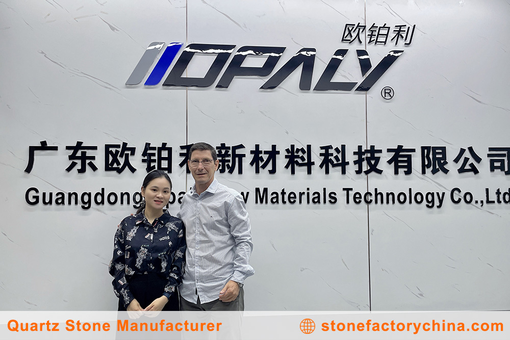 Supplier Partnership in Quartz Industry A sales manager and a client shaking hands in front of a selection of quartz slabs.